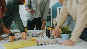Un collectif de travail réuni autour d'une table, penché sur des documents et des nuanciers de couleurs