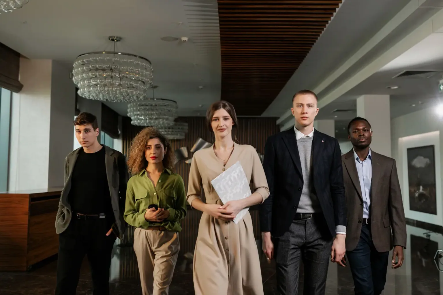 Un groupe de cinq associés se tient debout, côte à côte, dans le hall d'une entreprise