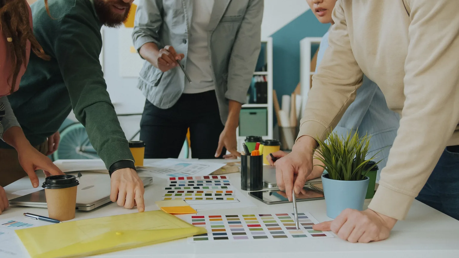Un collectif de travail réuni autour d'une table, penché sur des documents et des nuanciers de couleurs